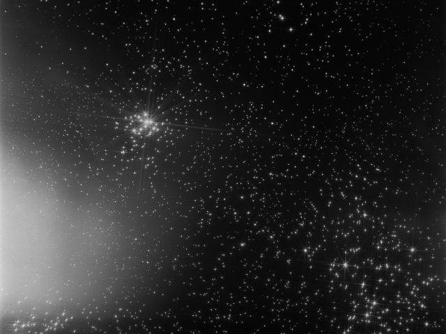 A black and white photograph of the night sky with many stars shining.