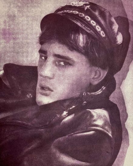 A pink-hued print of a man in a leather jacket with cap.