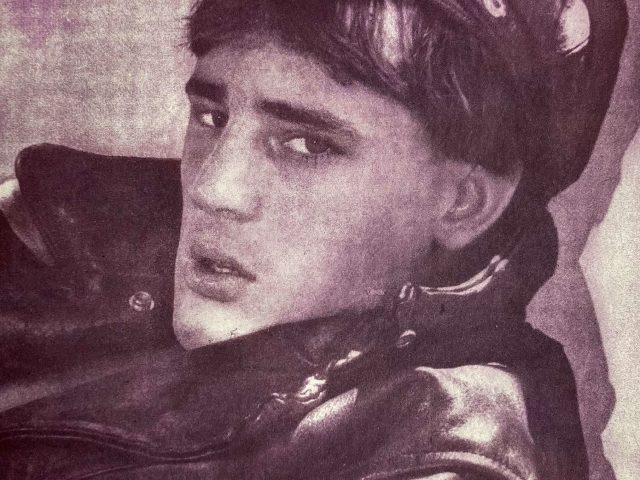 A pink-hued print of a man in a leather jacket with cap.