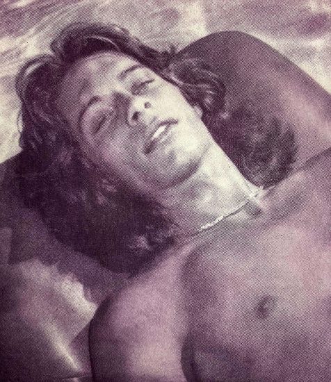 A pink-hued print of a boy with long hair lying by a pool.