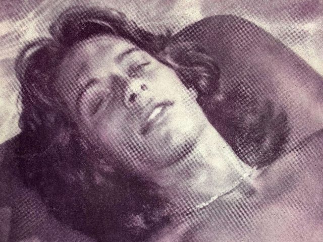 A pink-hued print of a boy with long hair lying by a pool.