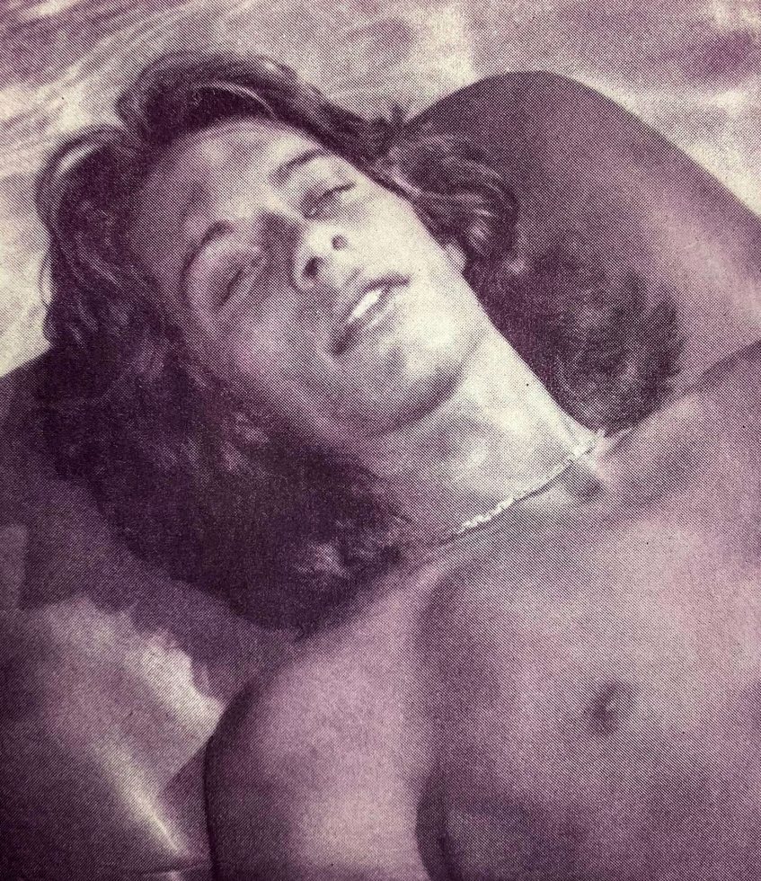 A pink-hued print of a boy with long hair lying by a pool.