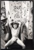A black-and-white photograph of a nude man in an easy chair seen from above.