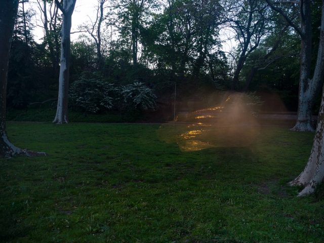 A color photograph of a grassy field at night.