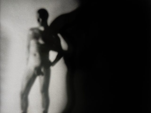 A black and white photograph of a nude man.