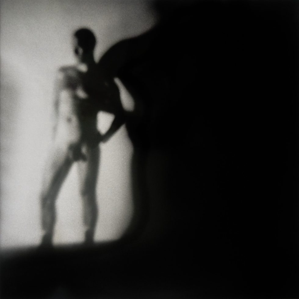 A black and white photograph of a nude man.