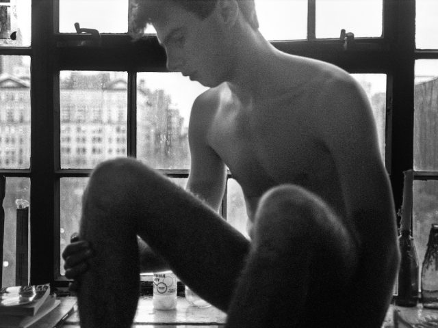 A black and white image of a boy sitting in a window.