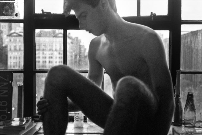A black and white image of a boy sitting in a window.