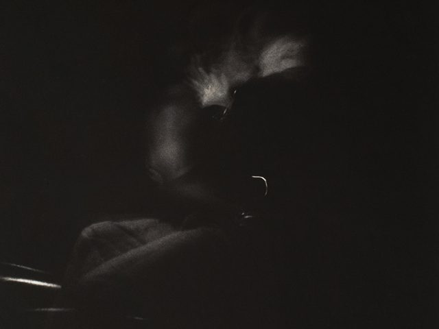 A black and white photograph of figures swimming at night.