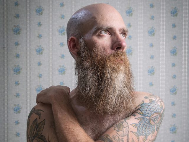 A color photograph os a shirtless man with a long beard.