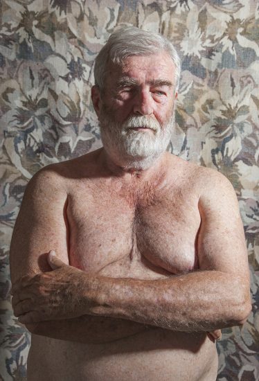 A color photograph of a shirtless older man with a white beard.