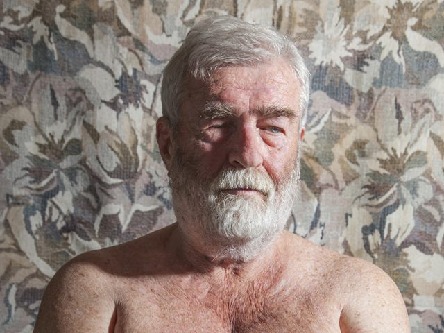 A color photograph of a shirtless older man with a white beard.