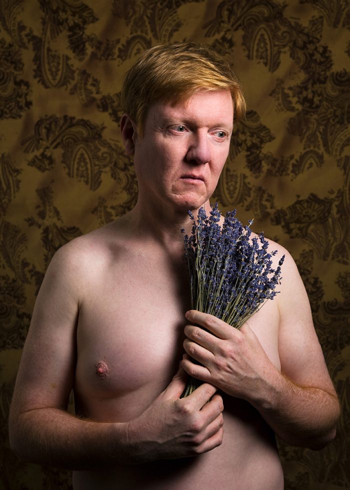A color portrait of a person holding lavender flowers.