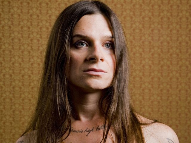 A color photograph of a shirtless woman with long hair.