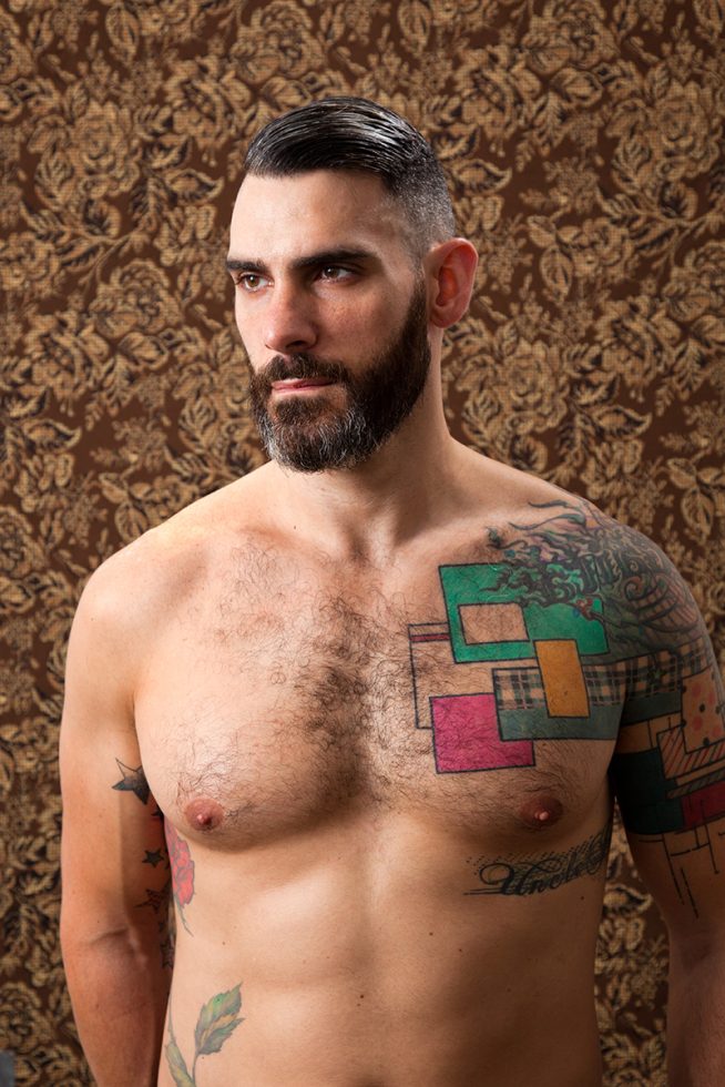 A color photograph of a shirtless man with a beard.