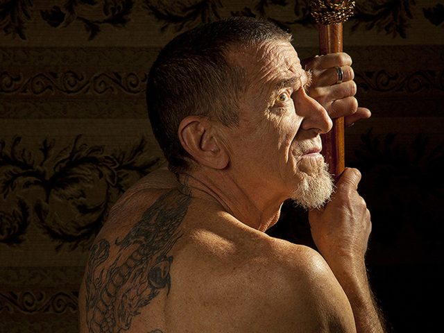 A color photograph of a man with a tattooed back facing away from the camera.