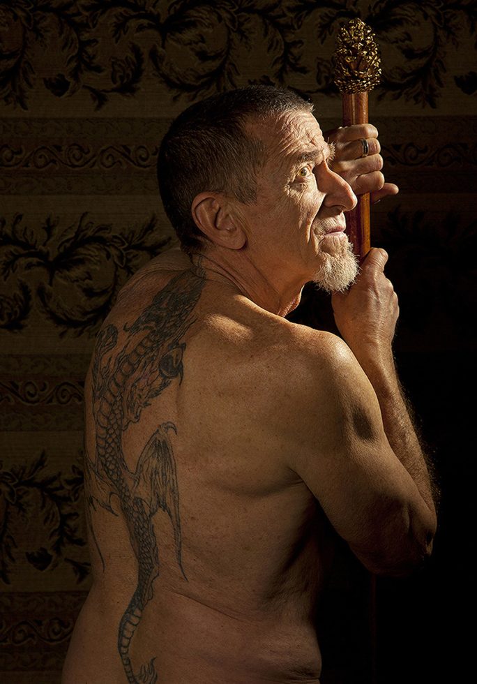 A color photograph of a man with a tattooed back facing away from the camera.
