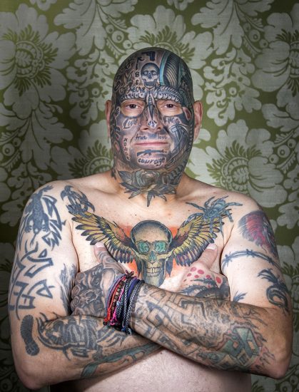 A color photograph os a shitless man with tattoos.