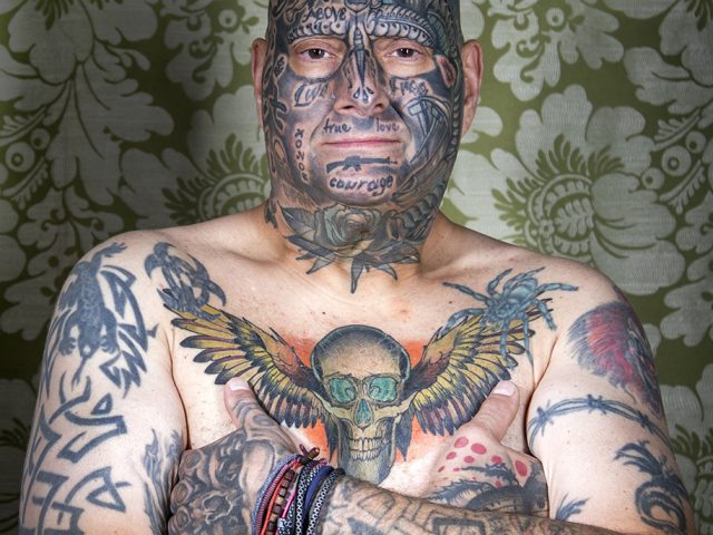 A color photograph os a shitless man with tattoos.
