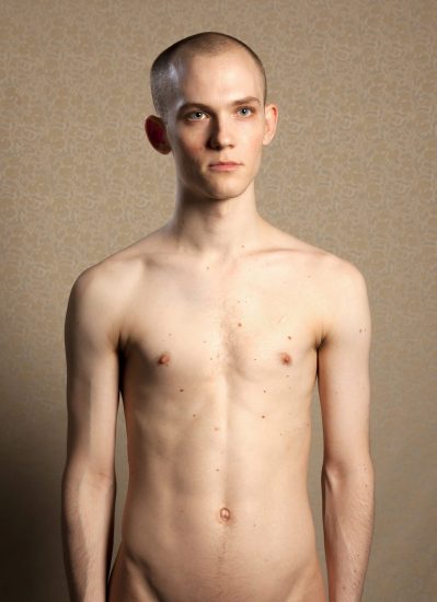 A color photograph of a shirtless young man.