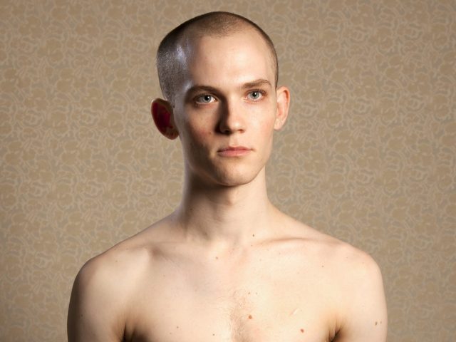 A color photograph of a shirtless young man.