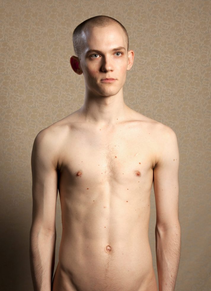 A color photograph of a shirtless young man.