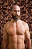 A color photograph of a shirtless man with a beard.