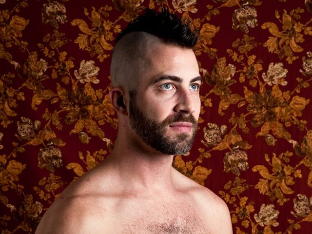 A color photograph of a shirtless man.