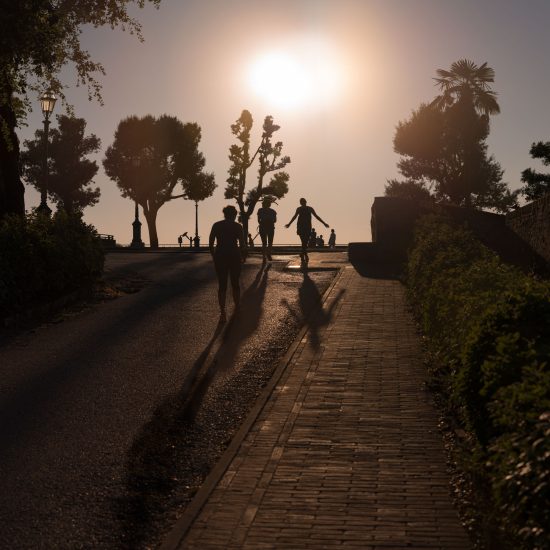 This is a color photograph of a group of people walking towards the sun as it sets.