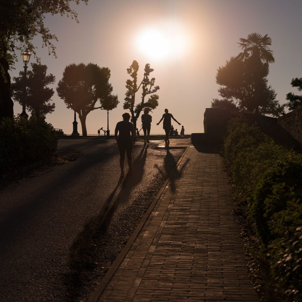 This is a color photograph of a group of people walking towards the sun as it sets.