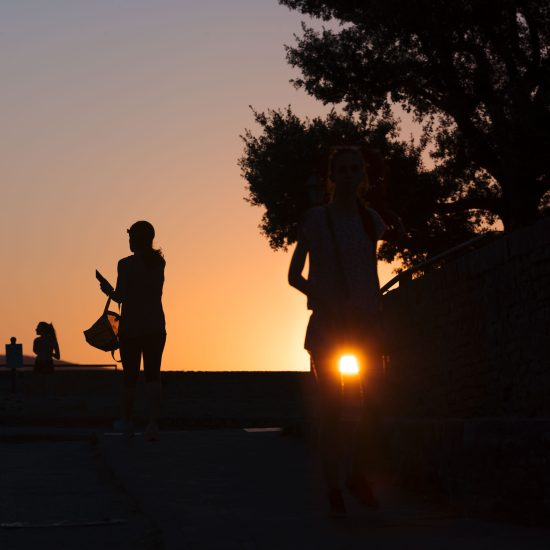 This is a color photograph of some one walking during sunset.