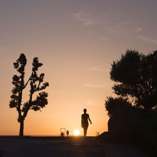 This is a color photograph of someone walking during sunset.