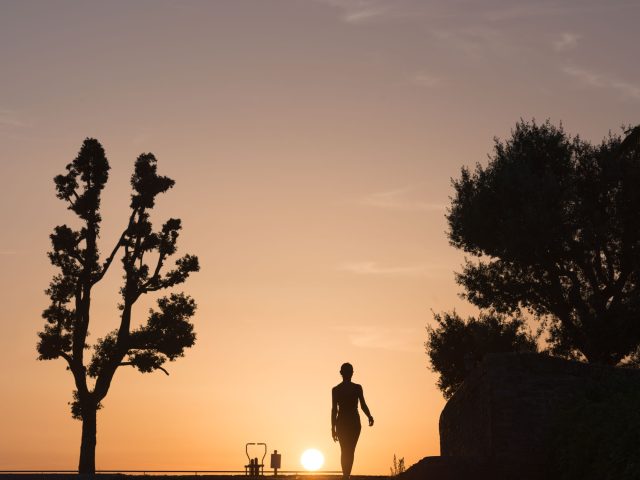 This is a color photograph of someone walking during sunset.