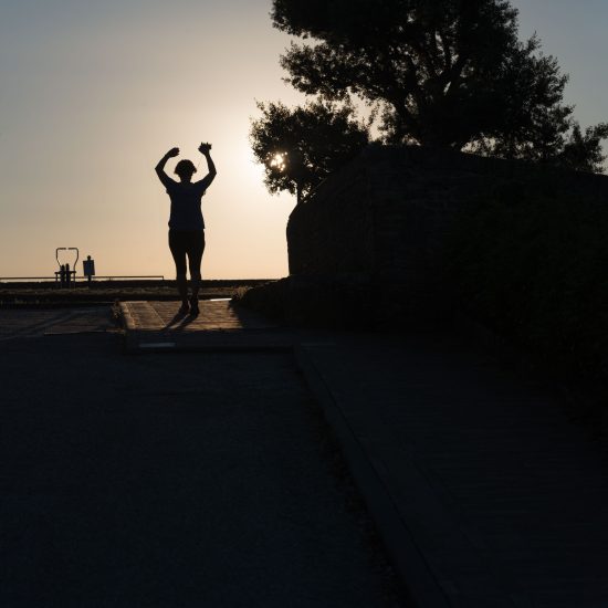 This is a color photograph of someone running towards the sunset.