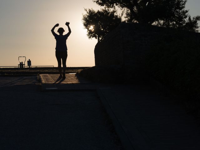 This is a color photograph of someone running towards the sunset.