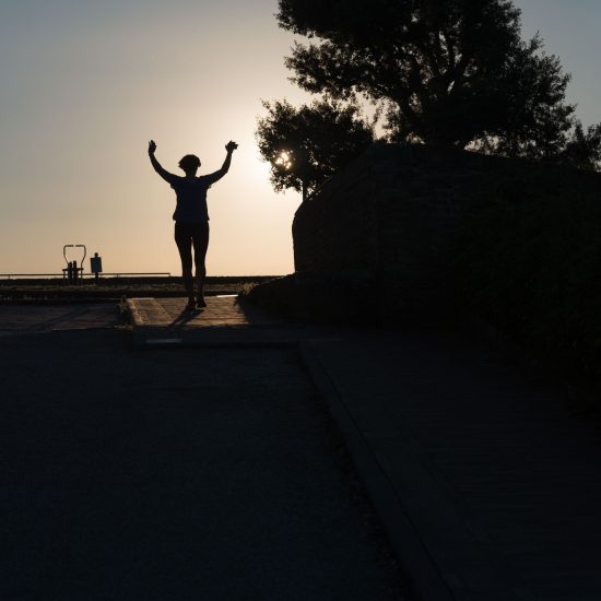 This is a color photograph of someone running towards the sunset.