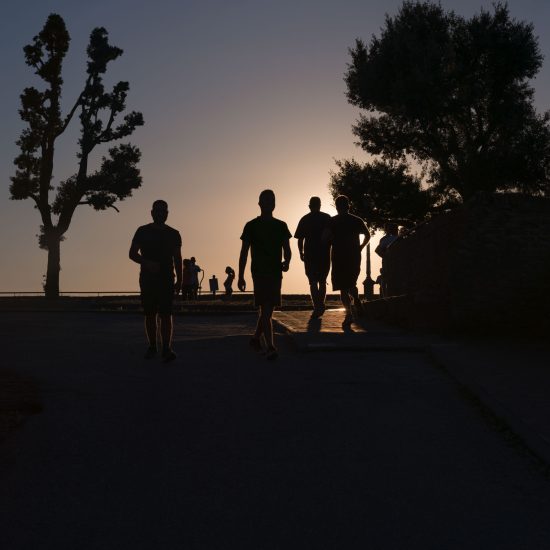 This is a color photograph of people walking in a park at sunset.