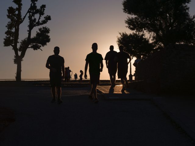 This is a color photograph of people walking in a park at sunset.