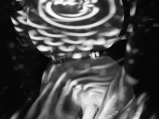 This image shows the body of a naked man from the waist down. A spiral of light covers the upper half of his chest.