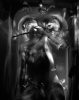 This black and white photograph shows a bathtub, seen from above, where the bodies of two seen are seen half submerged in water. Tubes run out of their mouths.