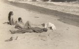 In this image, four figures are lounging on the sands of a beach.