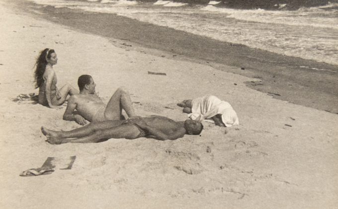 In this image, four figures are lounging on the sands of a beach.