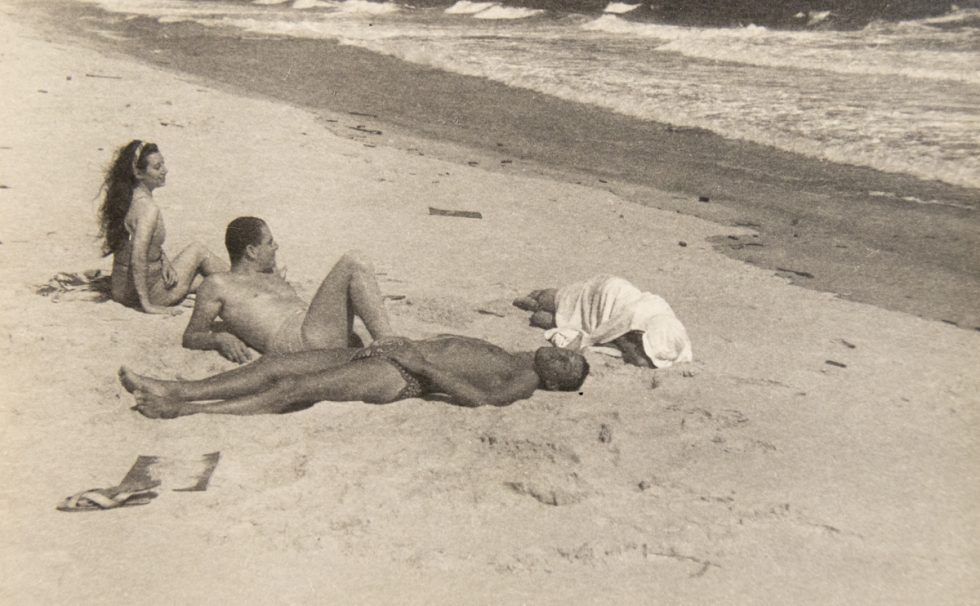 In this image, four figures are lounging on the sands of a beach.