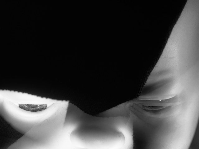 This black and white photograph shows the ghostly face of a baby. It's zoomed in on the baby's facial features, including its lips, nose, and eyes.