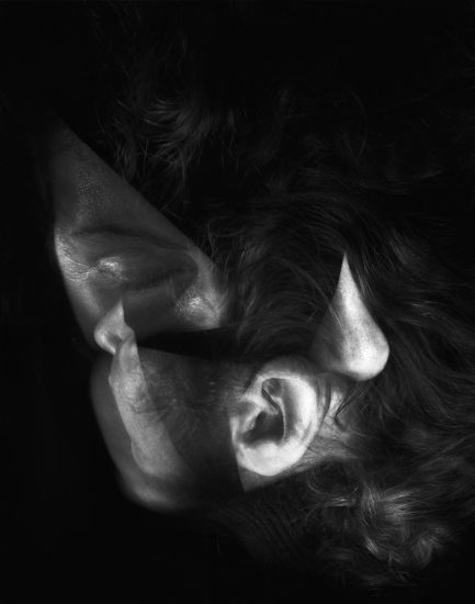 This image shows the contorted features of a man's head. His ear is near his nose at the bottom of the frame, where his hair also hangs.