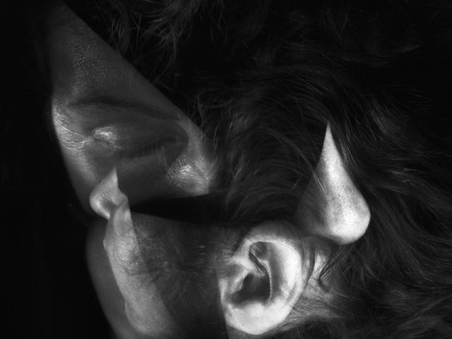 This image shows the contorted features of a man's head. His ear is near his nose at the bottom of the frame, where his hair also hangs.