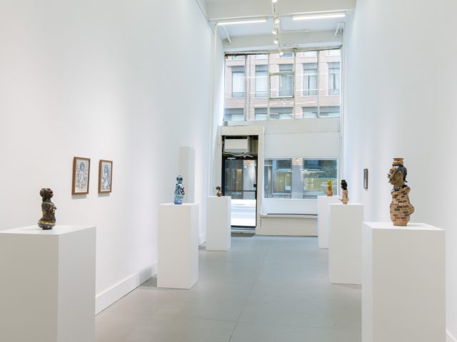In this image, a gallery with ceramic sculptures resting on pedestals is depicted.