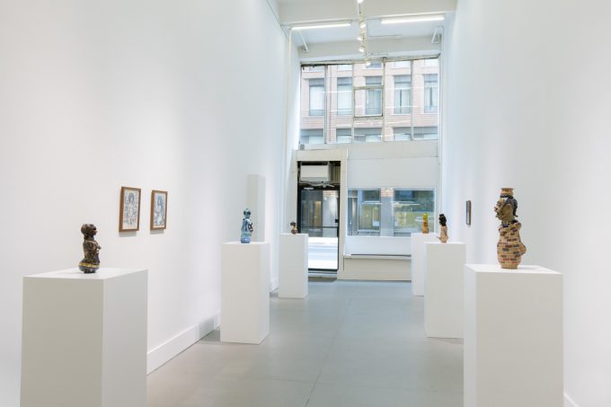 In this image, a gallery with ceramic sculptures resting on pedestals is depicted.