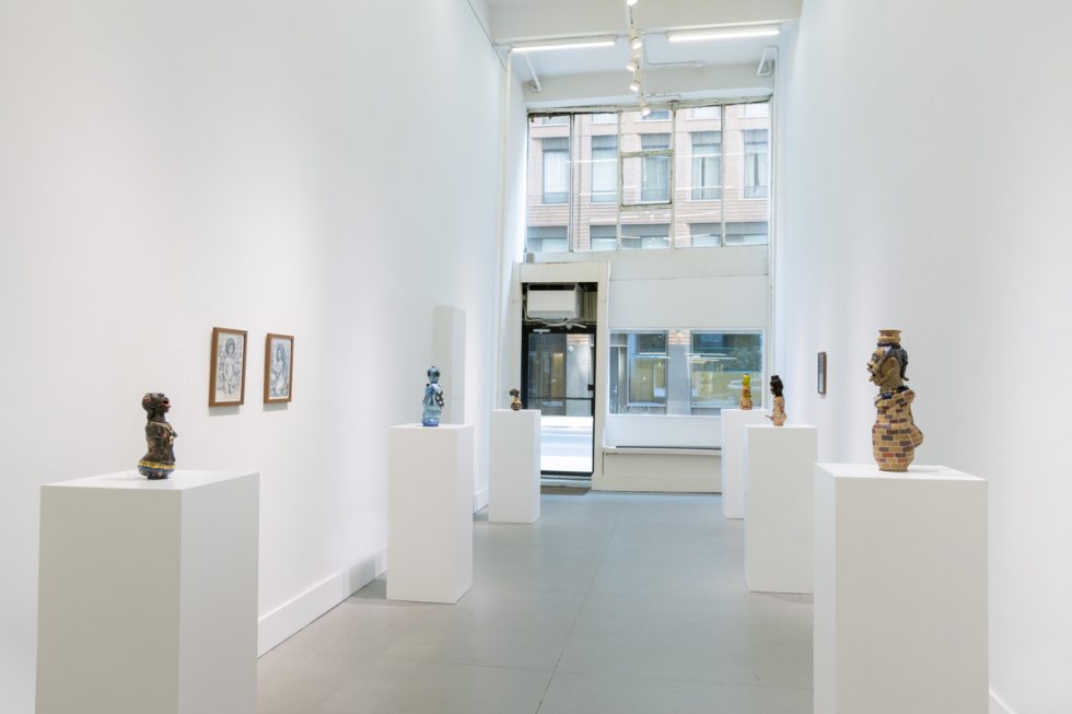 In this image, a gallery with ceramic sculptures resting on pedestals is depicted.
