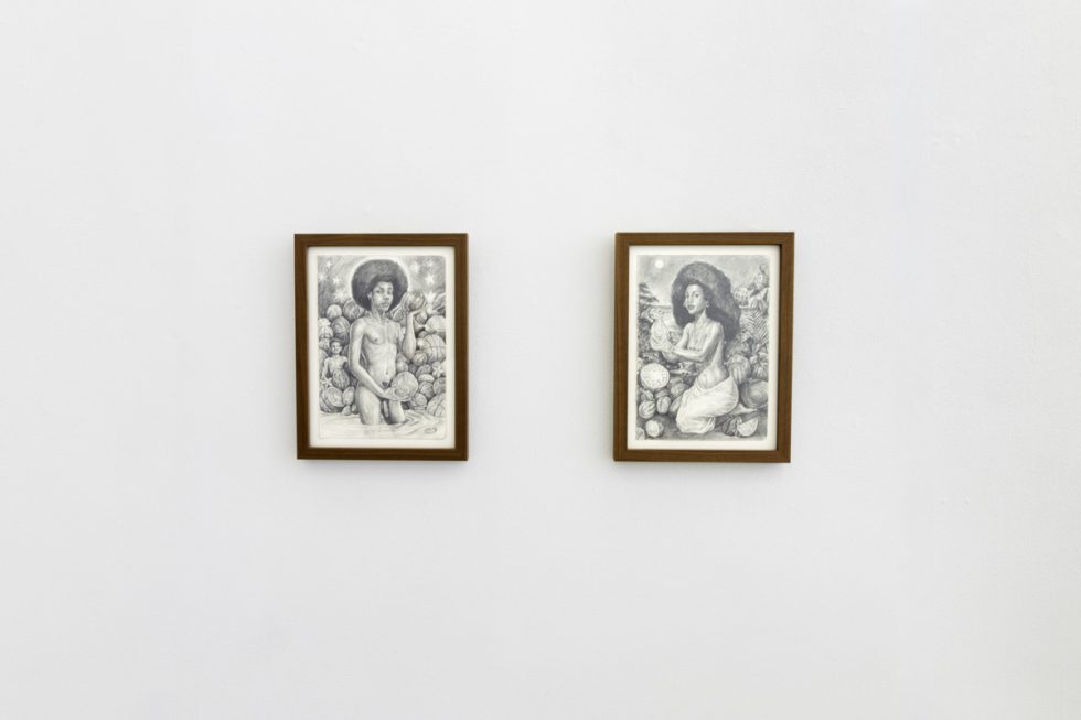 This photo shows two black and white drawings of women in nature hanging on a white wall.
